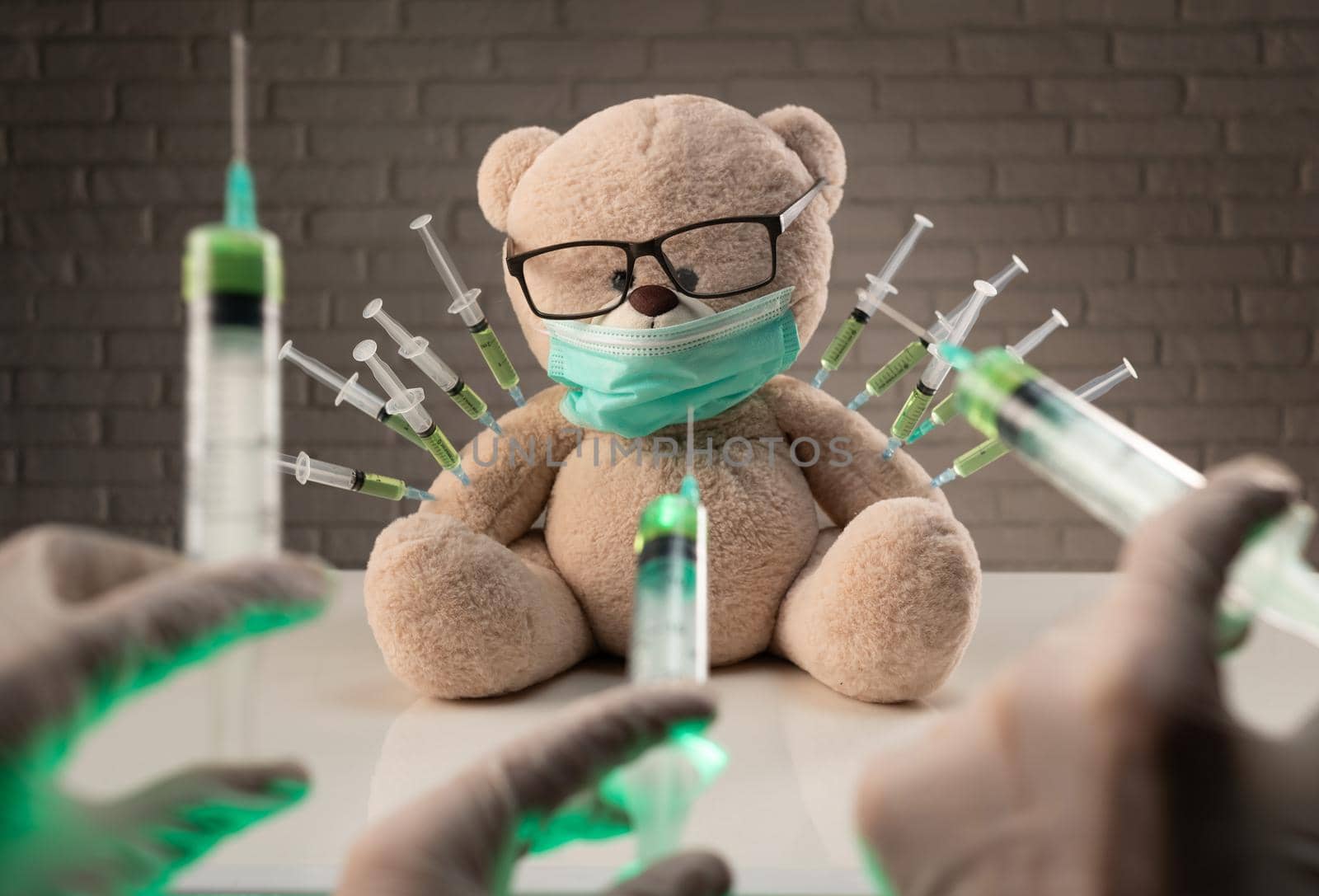 teddy bear in a medical mask with syringes in his shoulder on the doctor's table is given a second vaccination injection against the corona virus