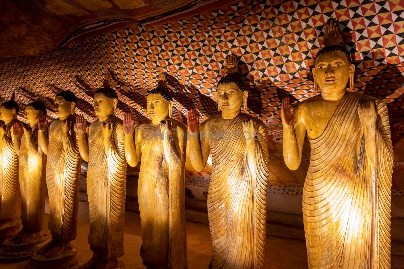 Sri Lanka. Dambulla Cave Temple. Buddha statues standing in a row, illuminated by lamps from below. High quality photo