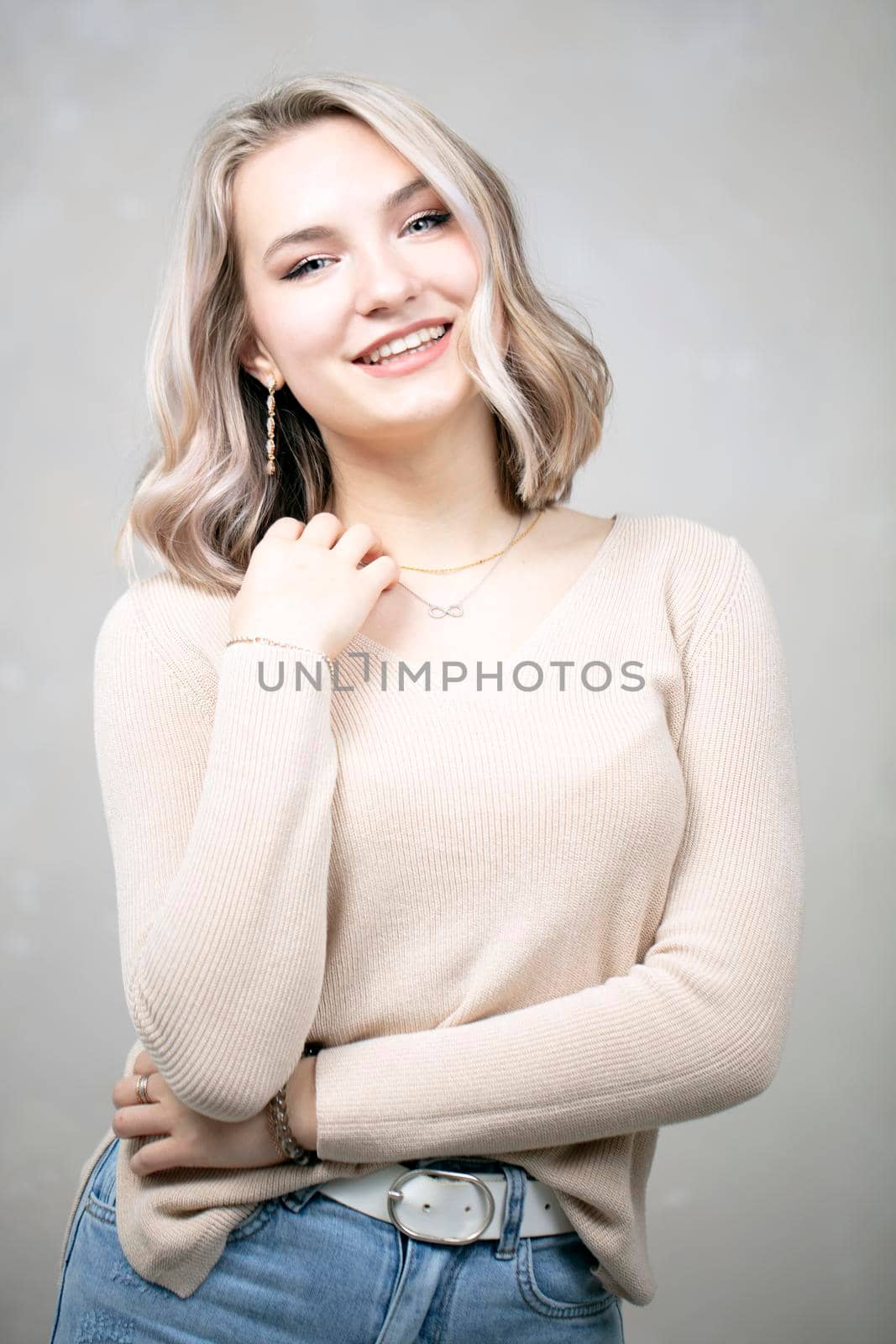 A beautiful young girl with blond hair and blue eyes looks at the camera and smiles.