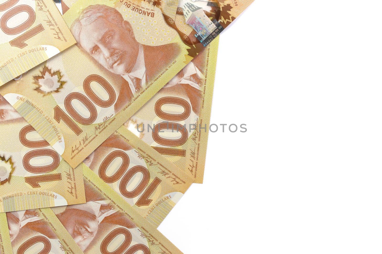 A Directly Above Image of Crisp Canadian 100 One Hundred Dollar Bills on a White Background. Banknotes are piled randomly on top of each other. Plenty of White Copy Space on Frame Right. High quality photo