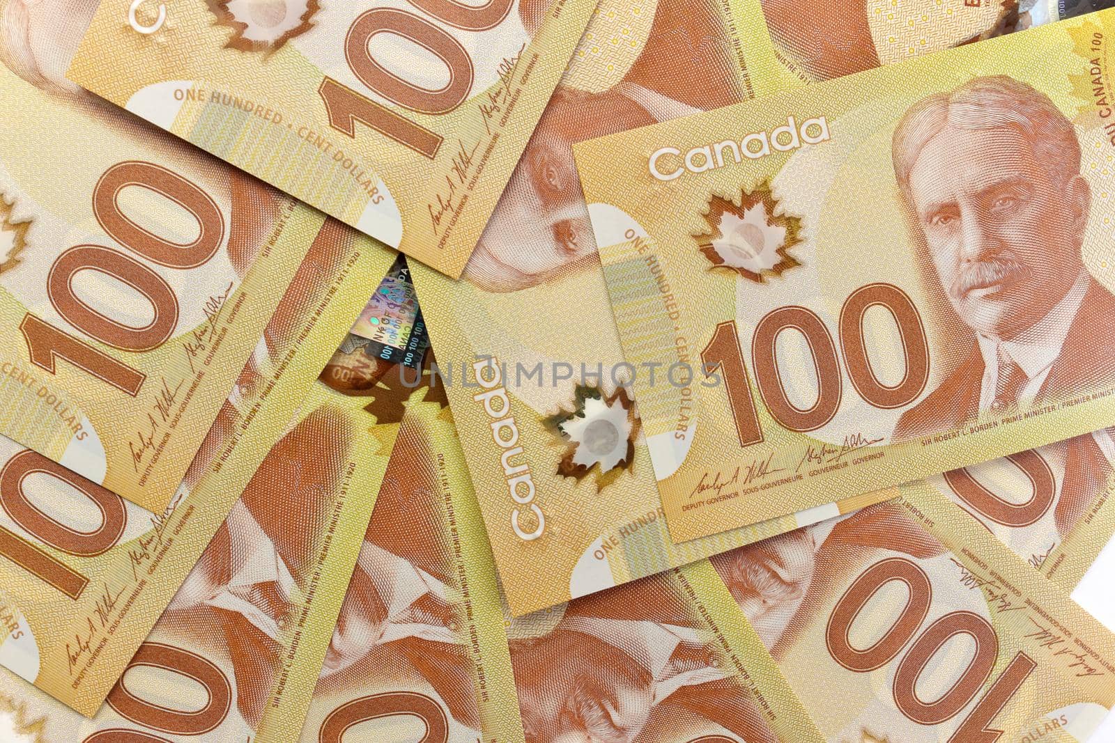 A Directly Above Image of Crisp Canadian 100 One Hundred Dollar Bills on a White Background. Banknotes are piled randomly on top of each other. Plenty of White Copy Space on Frame Right. High quality photo