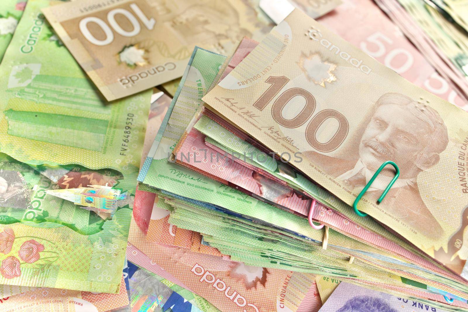 A High Angle View of Canadian Banknotes of Different Values. Banknotes are piled randomly on top of each other and have values of 5 five, 10 ten, 20 twenty, 50 fifty, and 100 one hundred dollars. Full Frame High quality photo