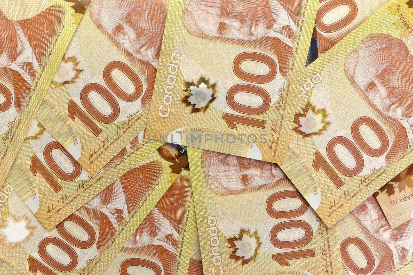 A Directly Above Image of Crisp Canadian 100 One Hundred Dollar Bills on a White Background. Banknotes are piled randomly on top of each other. Plenty of White Copy Space on Frame Right. High quality photo