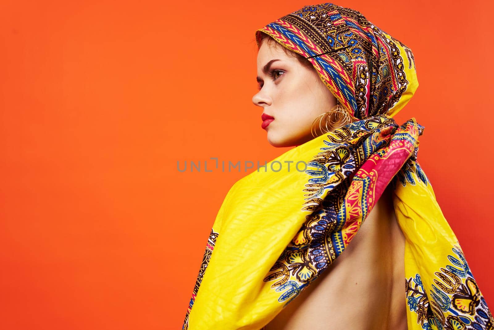 beautiful woman in multicolored turban attractive look Jewelry red background. High quality photo