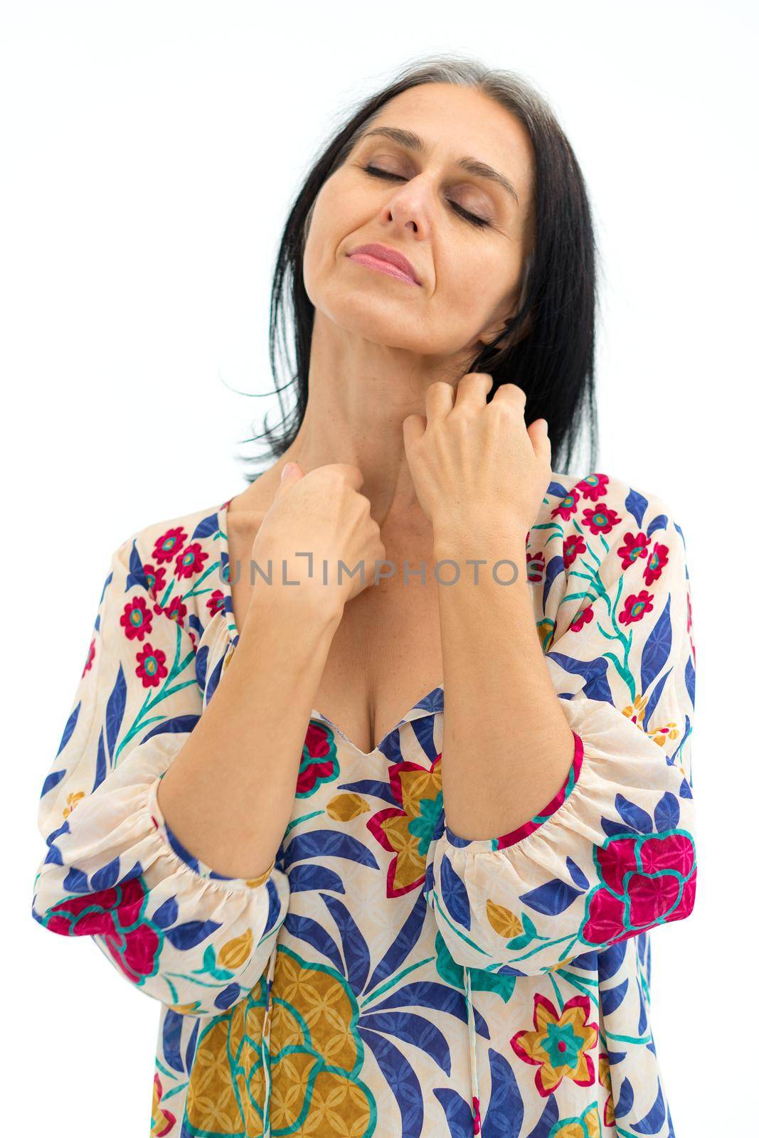 Studio photo of middle aged woman starting getting grey-haired wearing dress with flowers on white background, middle age sexy lady, cosmetology concept.