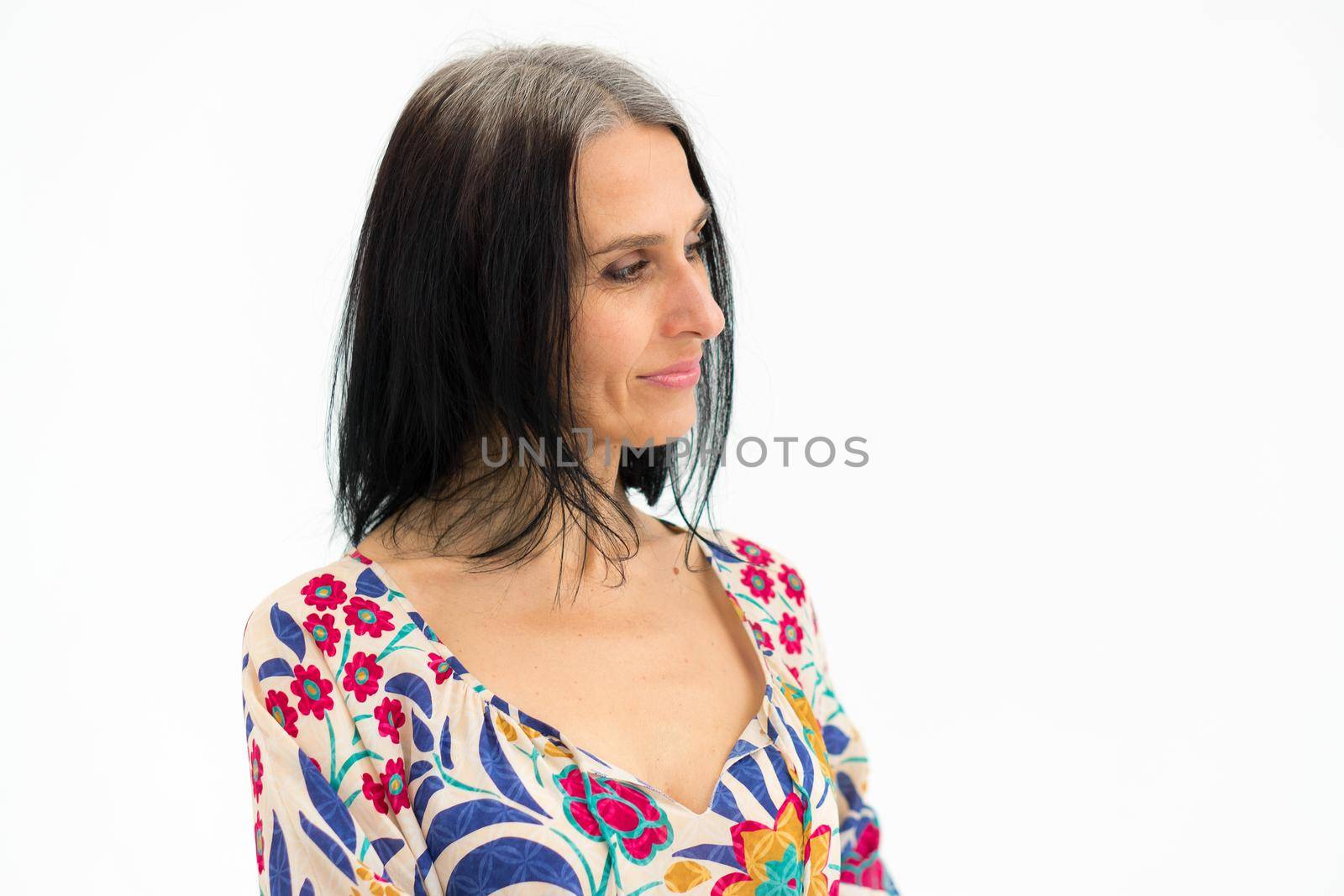 Close-up portrait of middle aged woman starting getting grey-haired wearing dress with flowers on white background, middle age sexy lady, cosmetology concept by balinska_lv