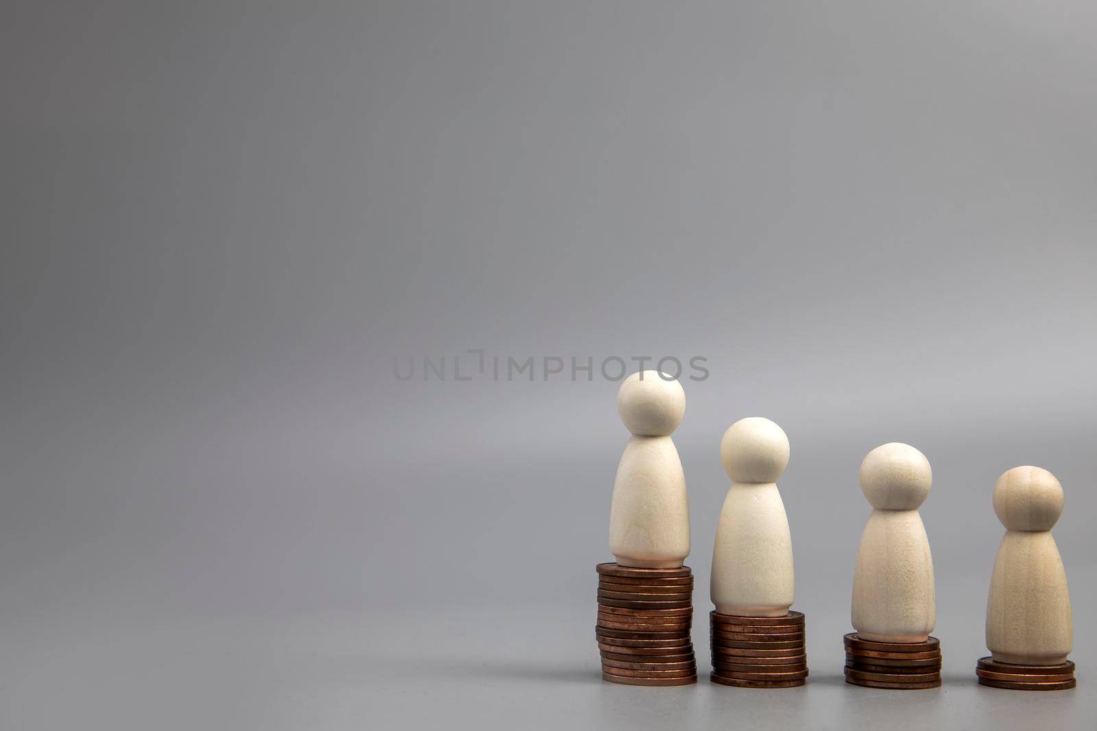 Miniature people standing on piles of different heights of coins. The concepts of person and wealth. investment and teamwork growth copy space