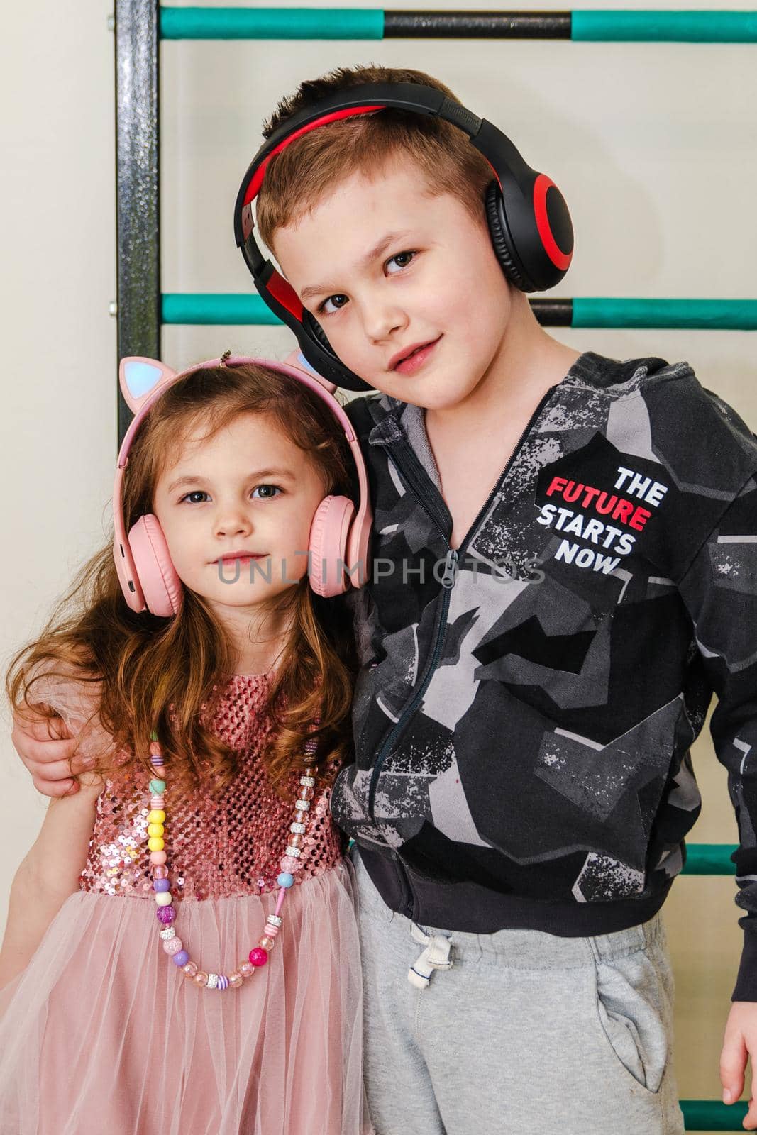 Little brother and sister at home in headphones, close-up.