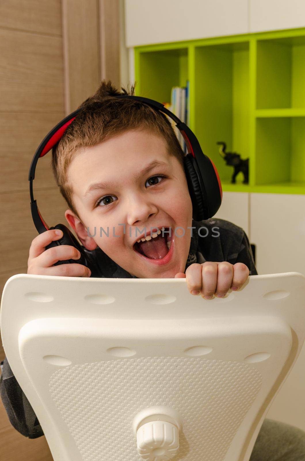 A little boy listens to music in wireless headphones at home, close-up.