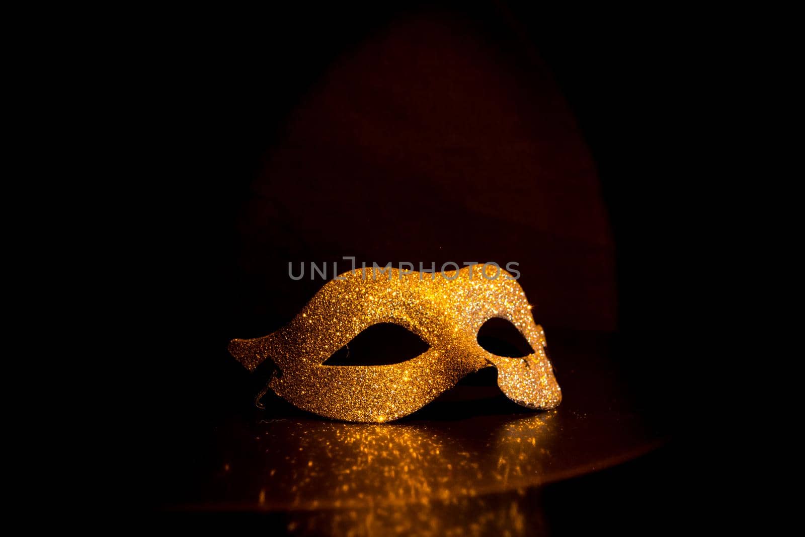 golden carnival mask under a halo of light on a black background