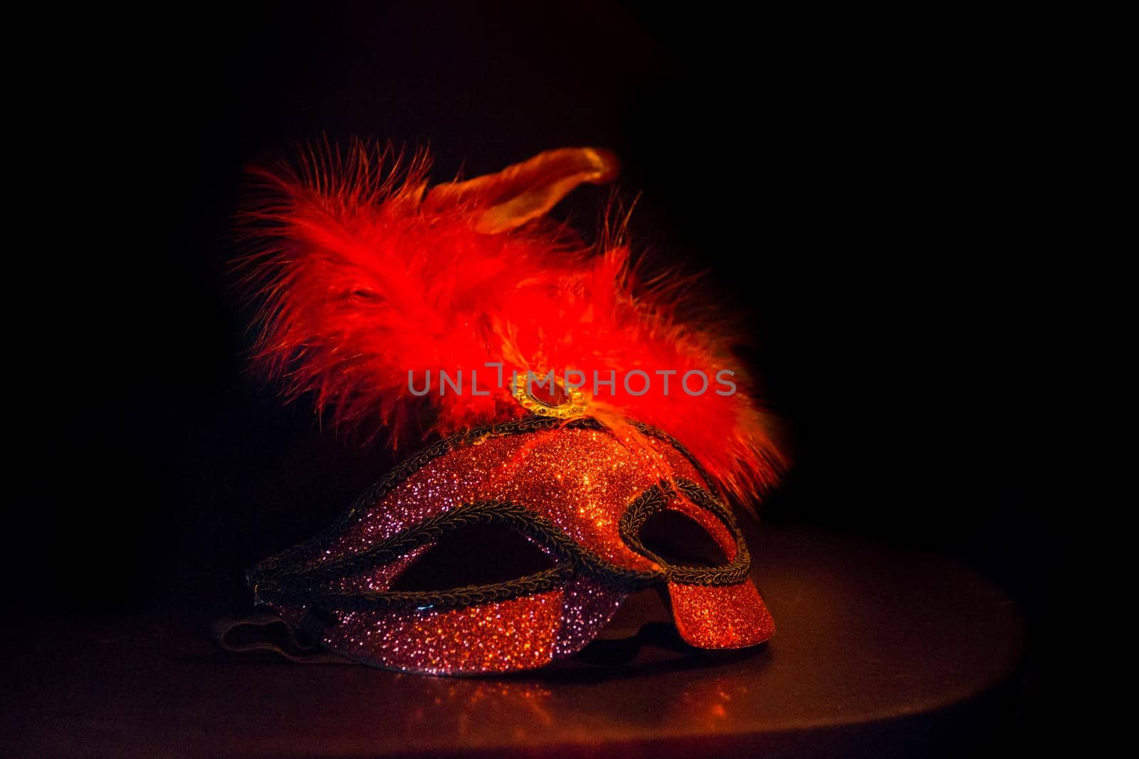 carnival symbol mask in red gold color with feathers on black background