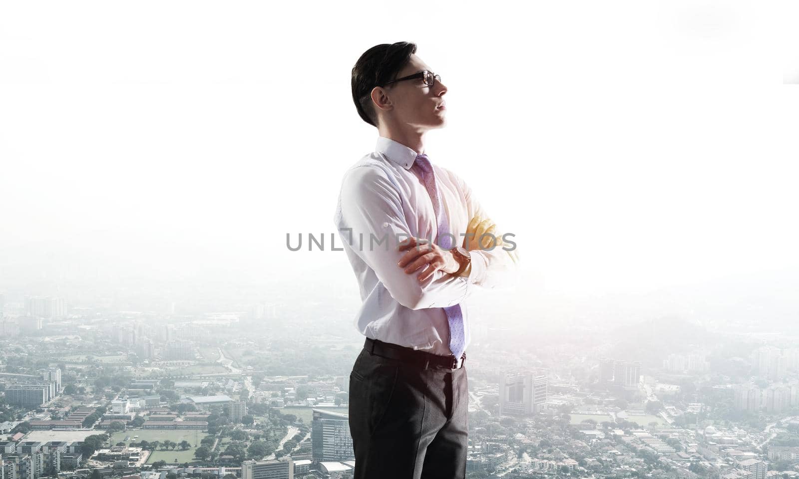 Young elegant businessman with arms crossed on chest looking away
