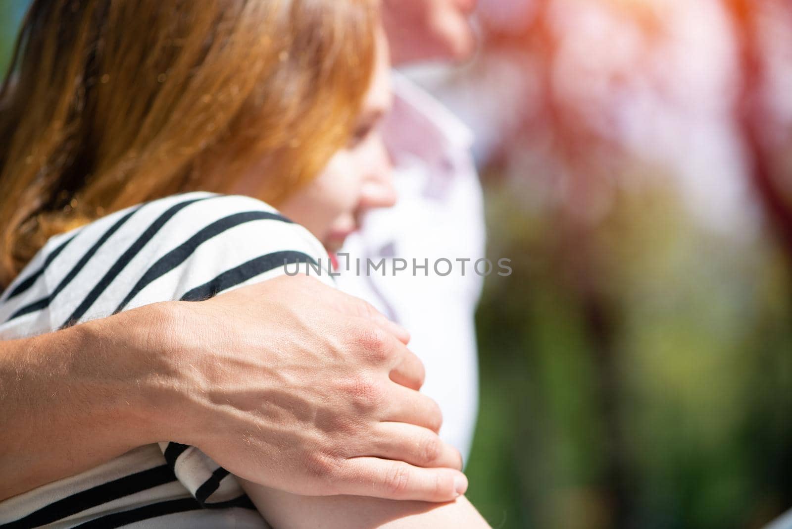 A young man hugs a woman. Sitting hugging in the park