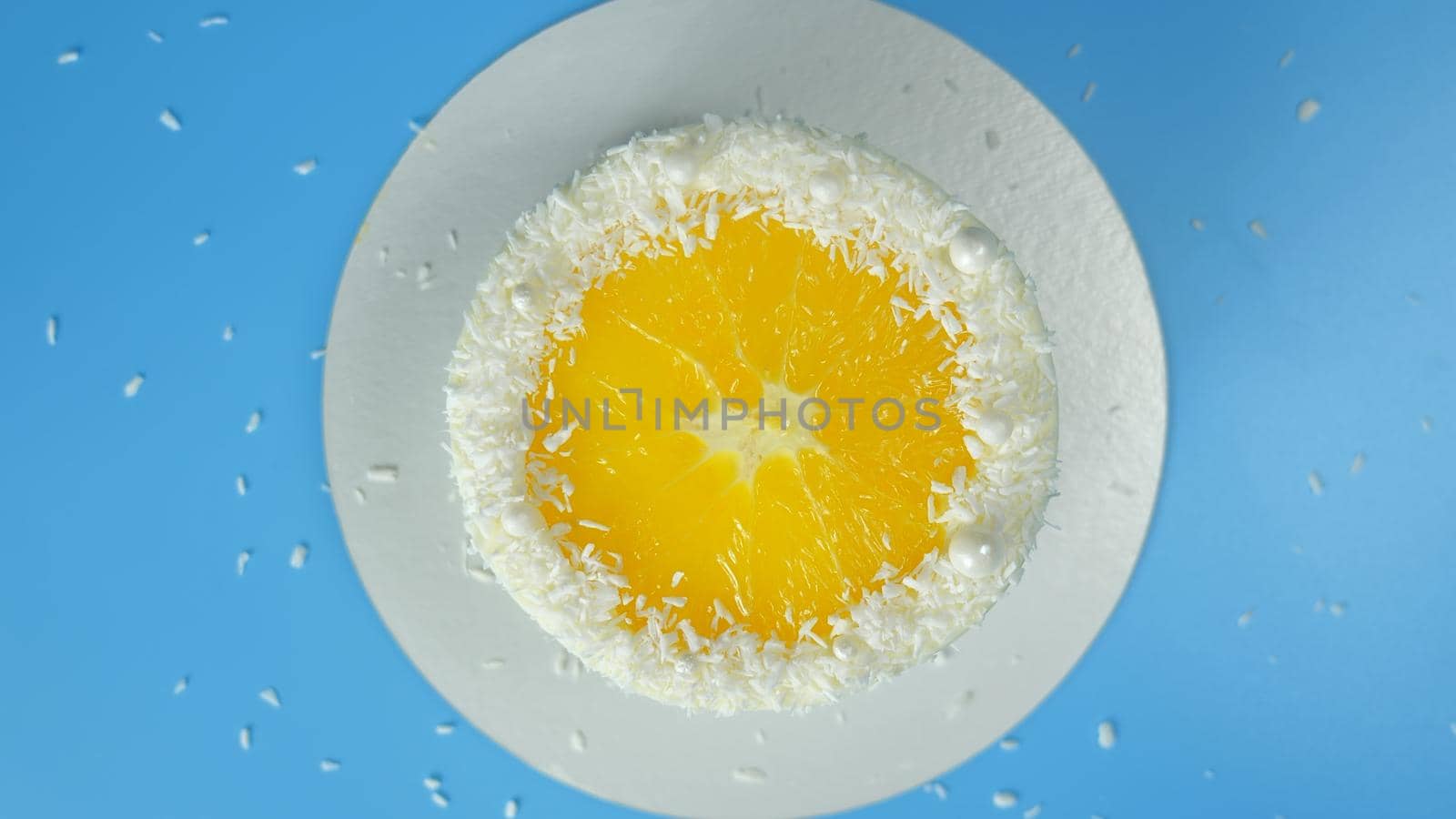 Cake with a cut orange and coconut on a blue background. by DovidPro