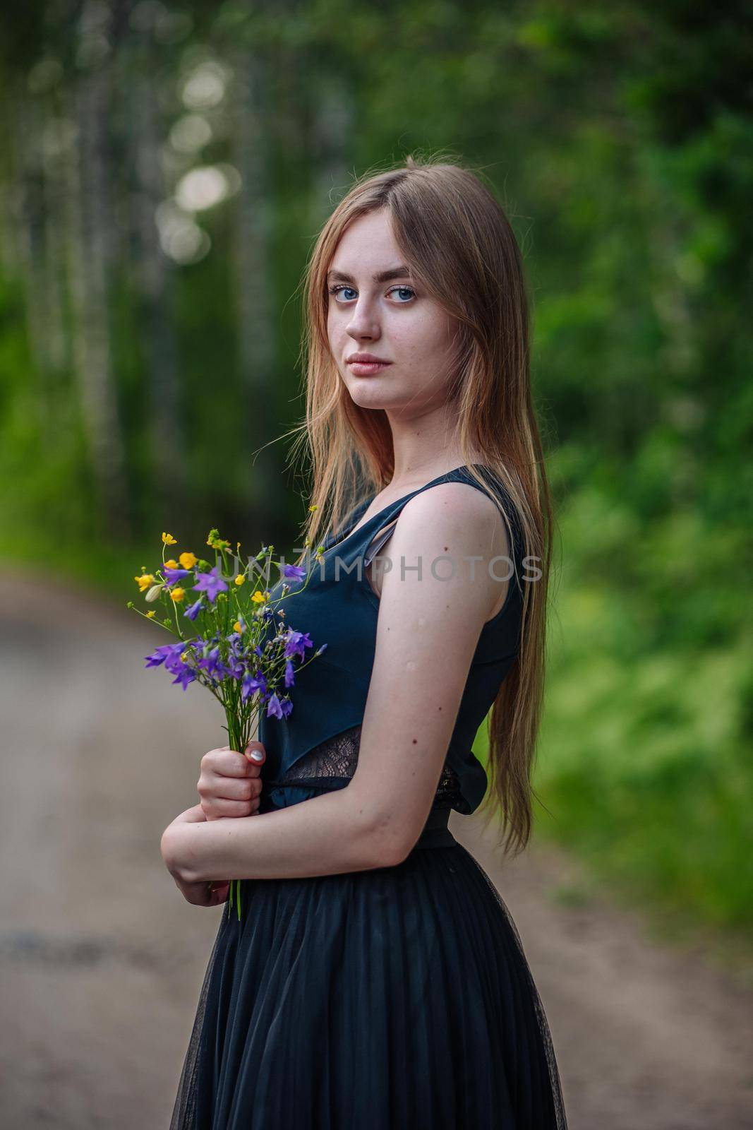 Portrait of a Russian girl with a bouquet of wild flowers in the evening at the village