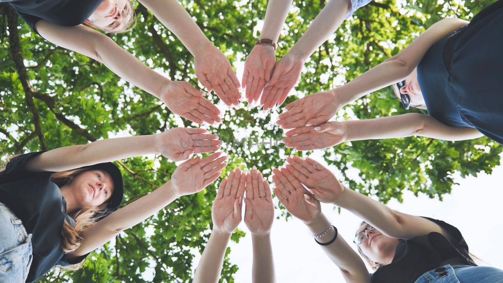 Girlfriends join the palms of their hands in the center making a circle shape