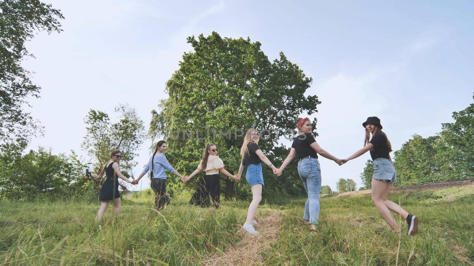 Schoolgirl friends are walking outside the city along a forest road. by DovidPro