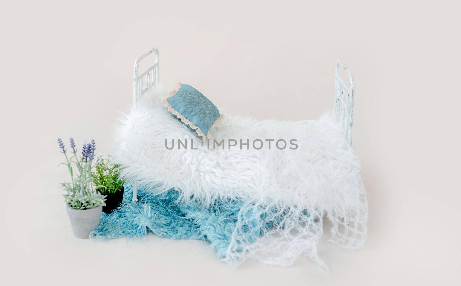 Newborn baby studio furniture tiny bed with fur decorated with flower plant. Beautiful spot for infant child studio photoshoot