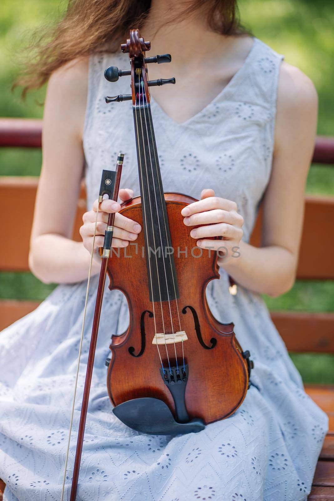 A young girl holds a violin in her hand and touches the strings. by DovidPro