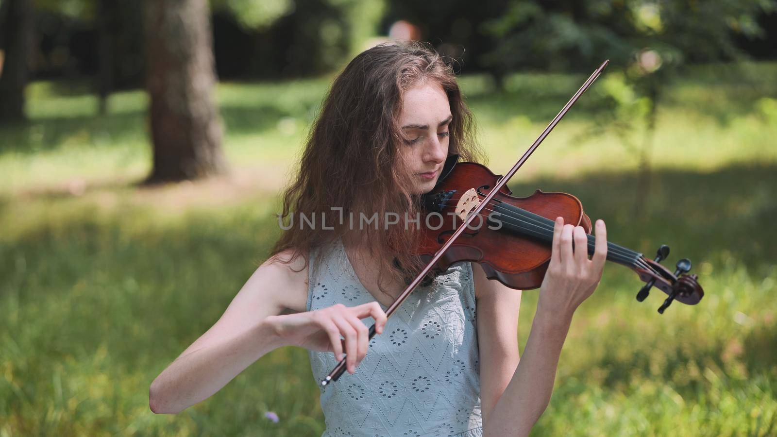 A young girl plays the violin in the city park