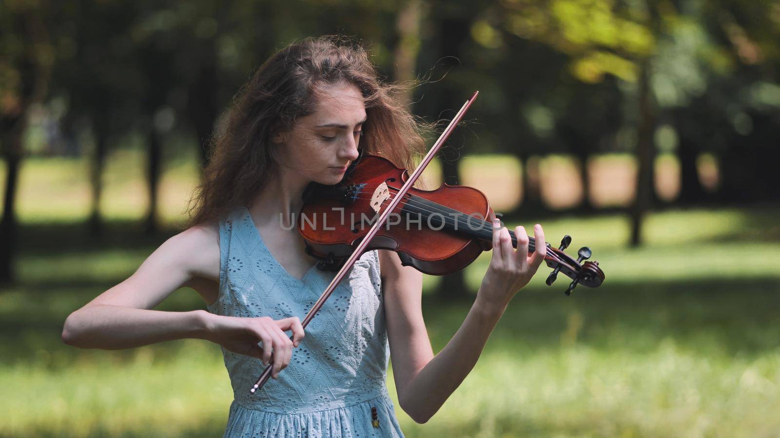 A young girl plays the violin in the city park