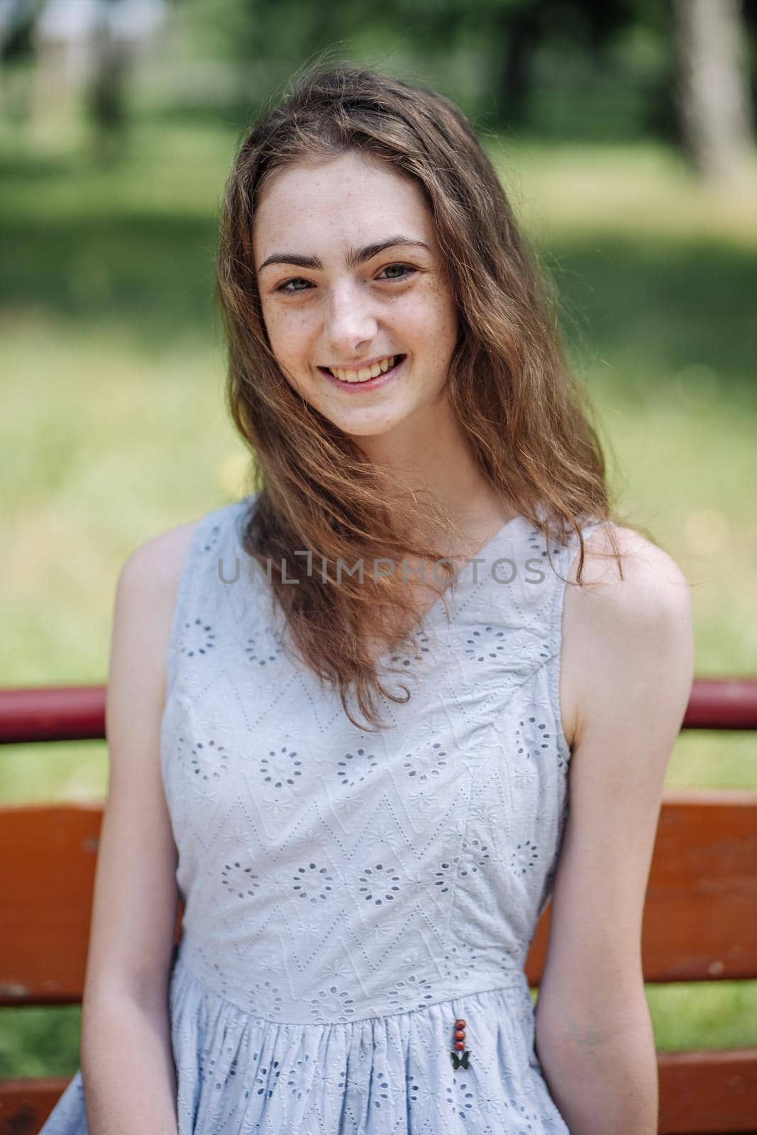 Portrait of a young smiling girl on a park bench