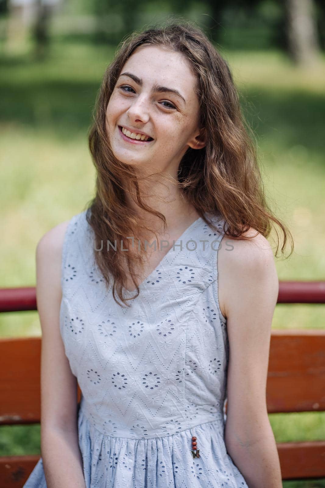 Portrait of a young smiling girl on a park bench. by DovidPro