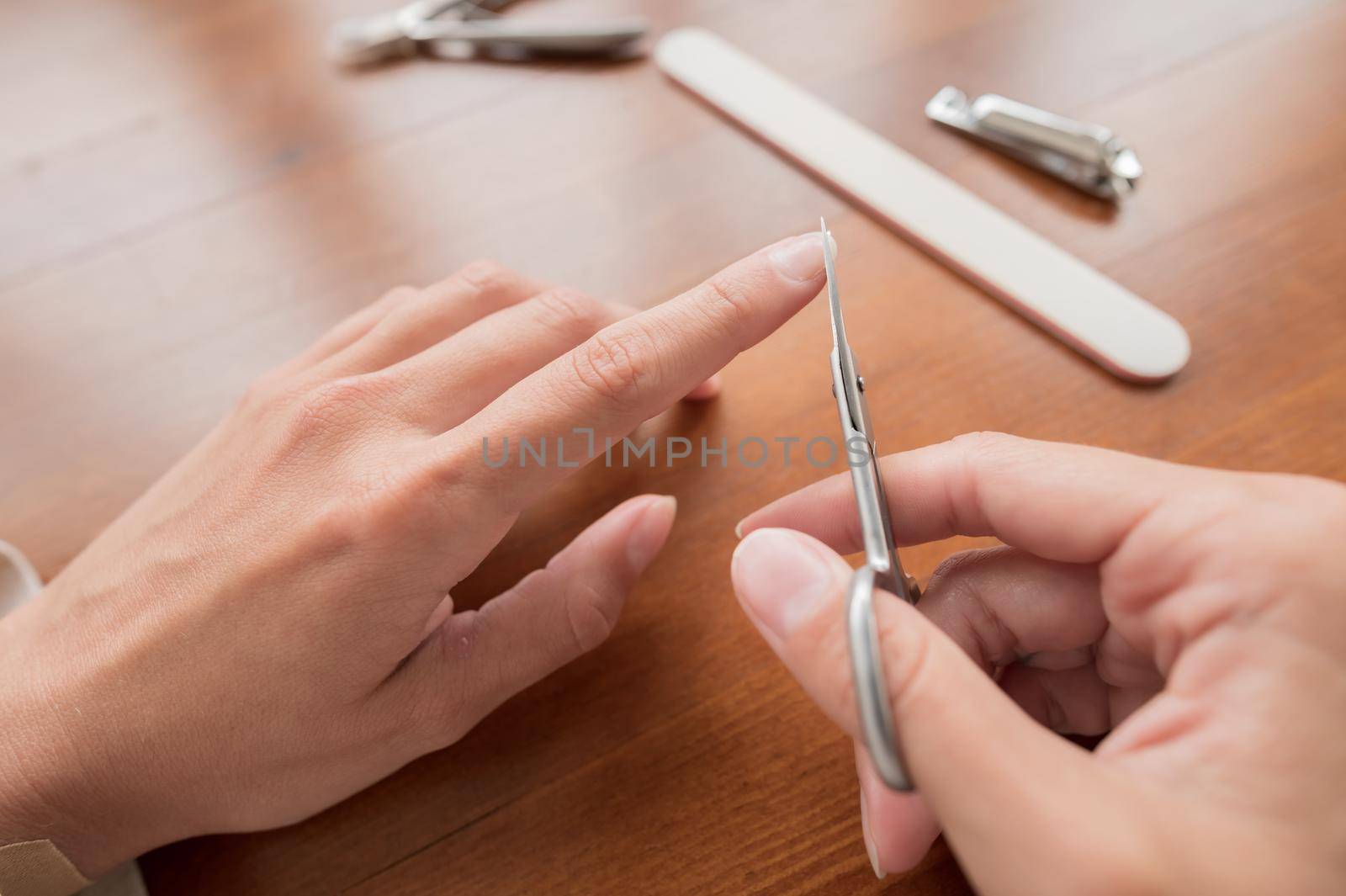 Close-up of hand of caucasian young woman doing manicure scissors, cut at home with nail supplies