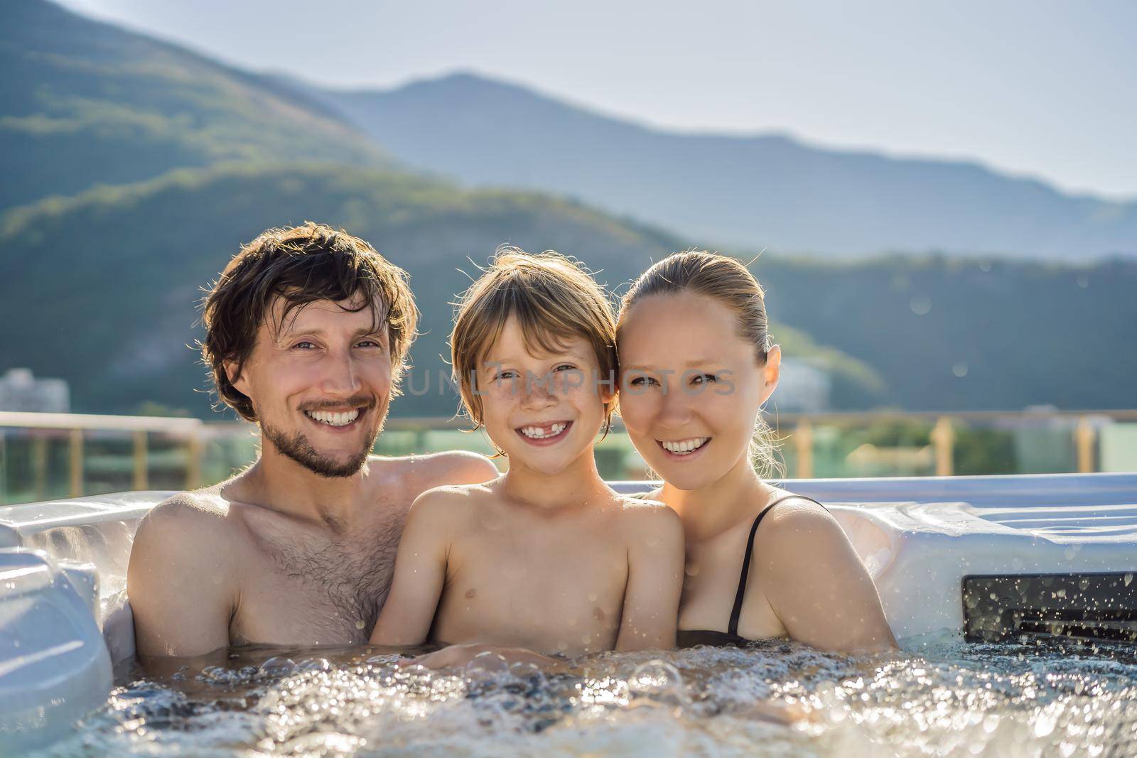 Portrait of young carefree happy smiling happy family relaxing at hot tub during enjoying happy traveling moment vacation. Life against the background of green big mountains.