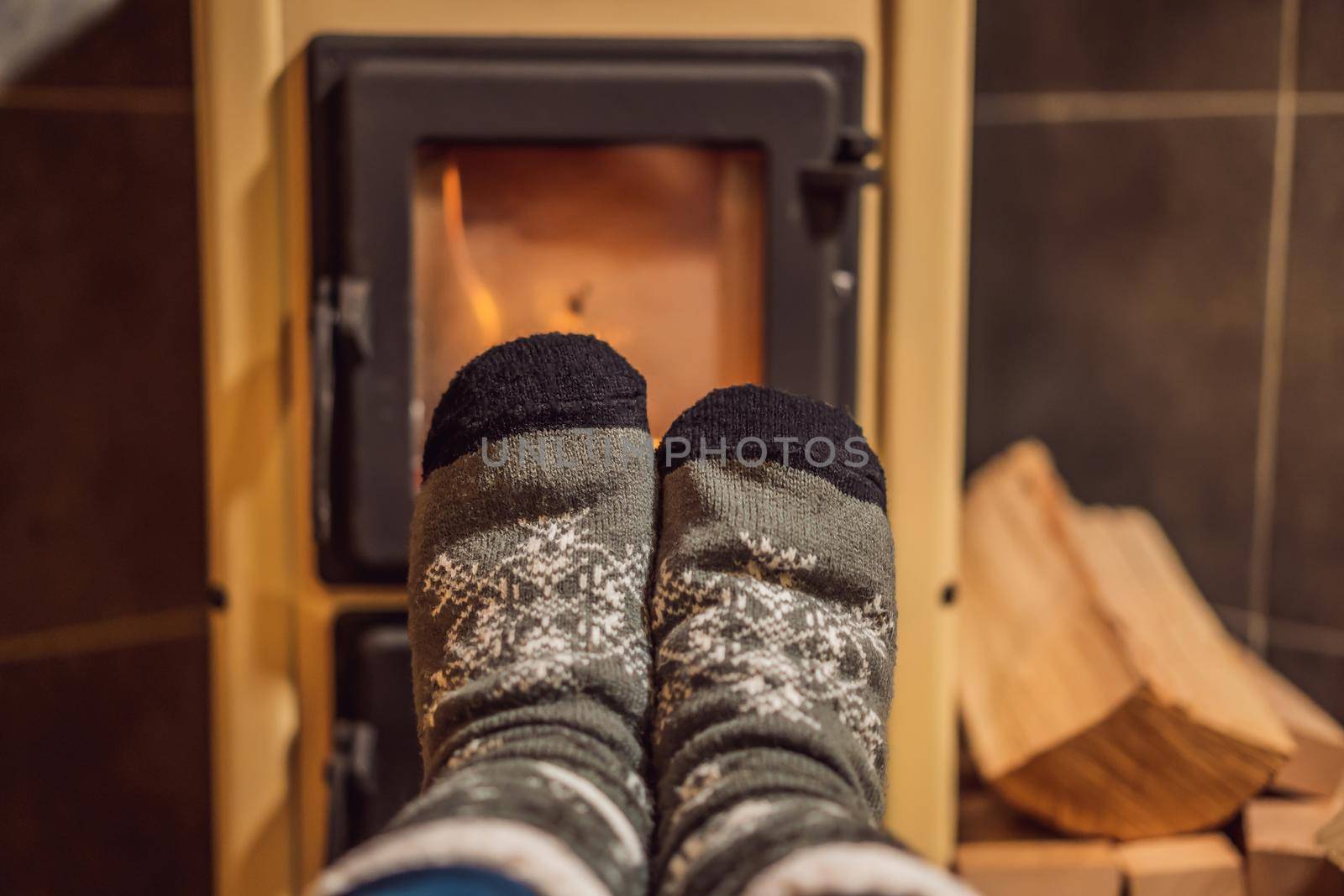 Feet in winter socks are heated by the fireplace. Rest in the mountains in Glamping. Cozy fireplace in a mountain house.