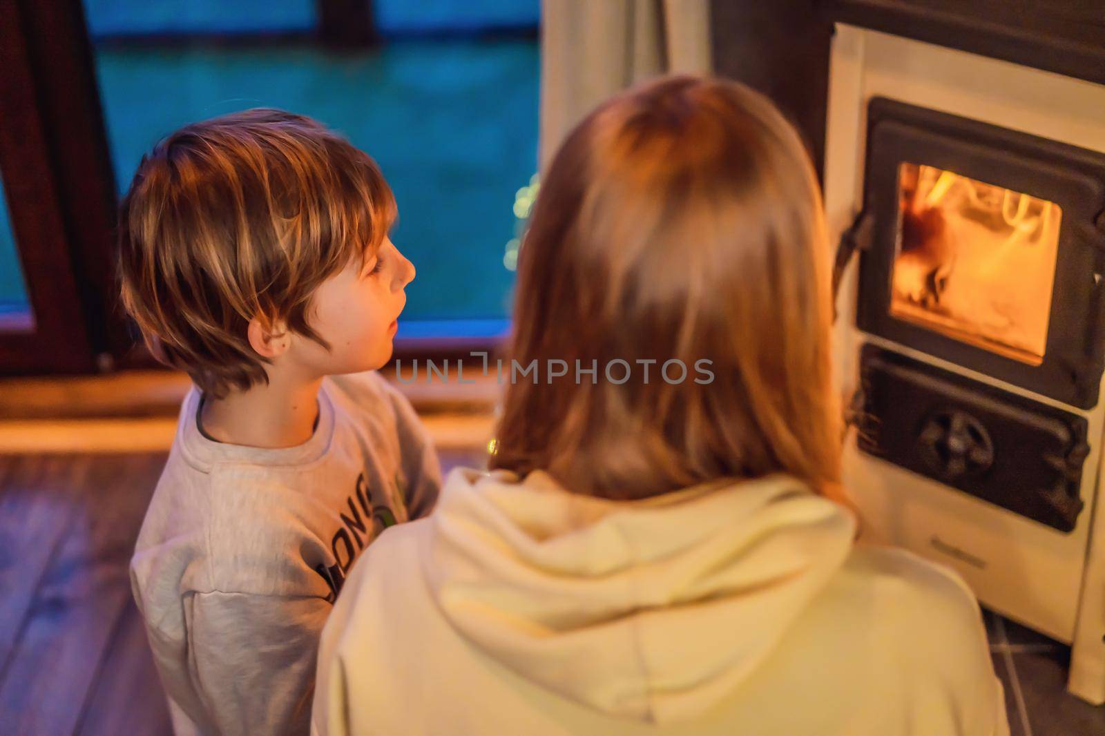 Mom and son spend time by the fireplace in Glamping. Rest in the mountains in Glamping. Cozy fireplace in a mountain house.