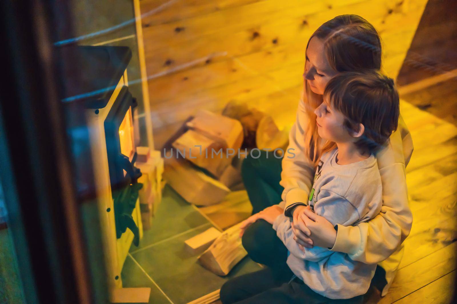 Mom and son spend time by the fireplace in Glamping. Rest in the mountains in Glamping. Cozy fireplace in a mountain house by galitskaya