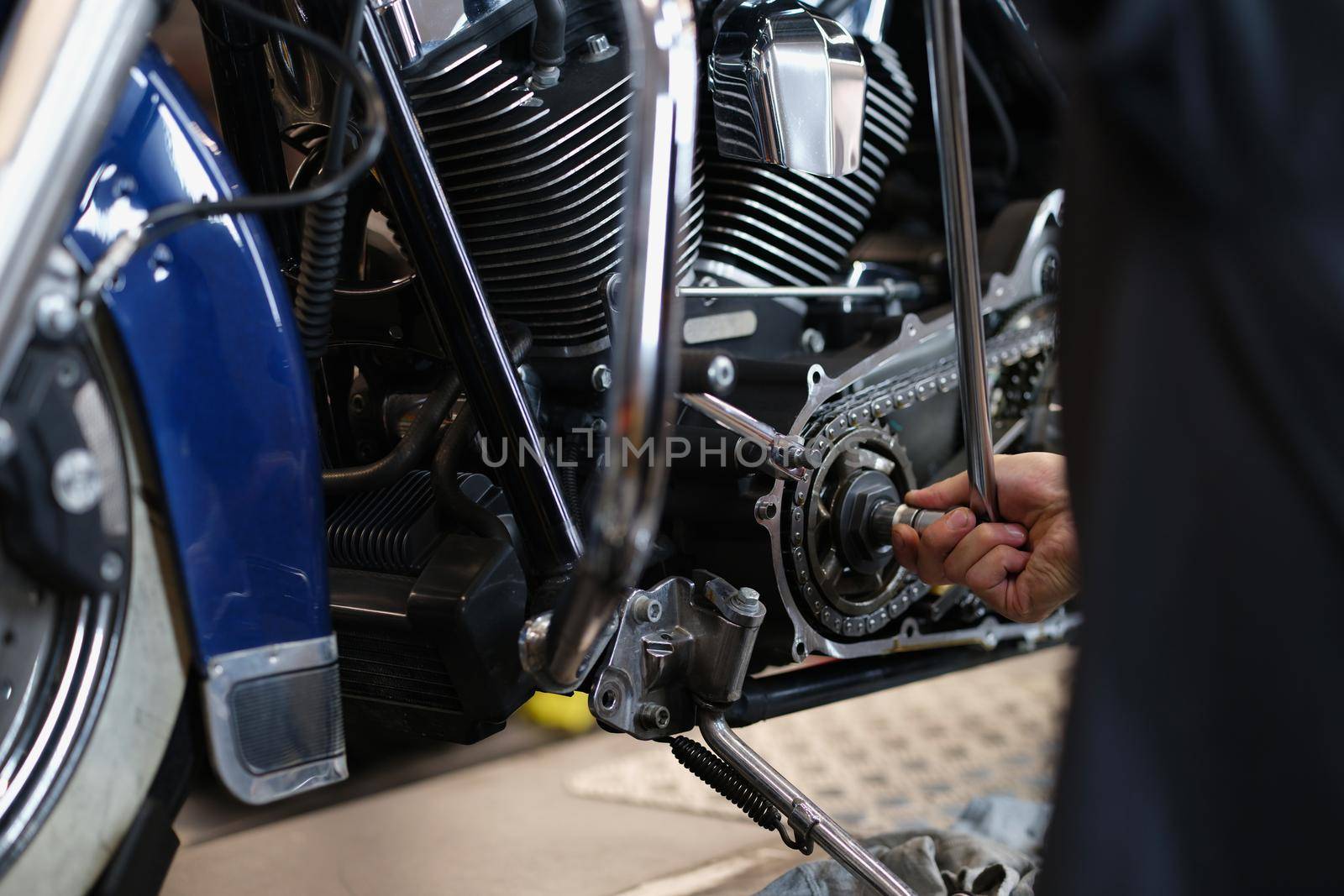 Close-up of professional mechanic fixing part of motorbike transport with wrench instrument. Pit stop for vehicle to get help. Maintenance service concept