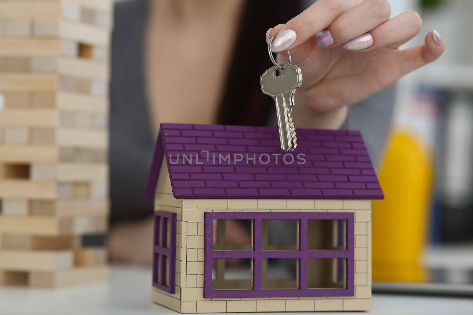 Female worker hand hold key to unlock new miniature toy house, buy new accommodation by kuprevich