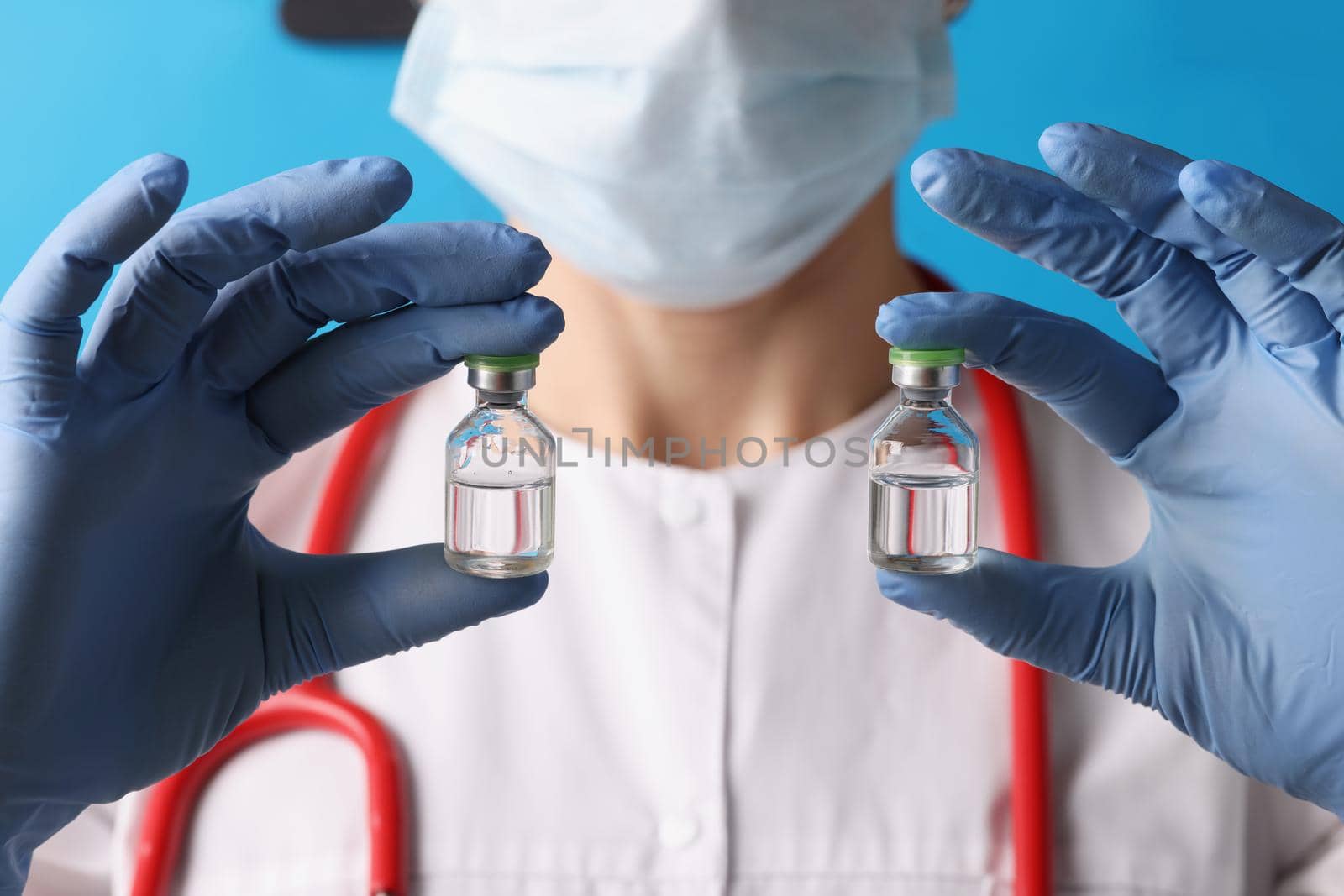 Close-up of scientist holding two bottles with injection in blue gloves. Dose of chemical substance in laboratory. Vaccination, analysis, test, lab concept