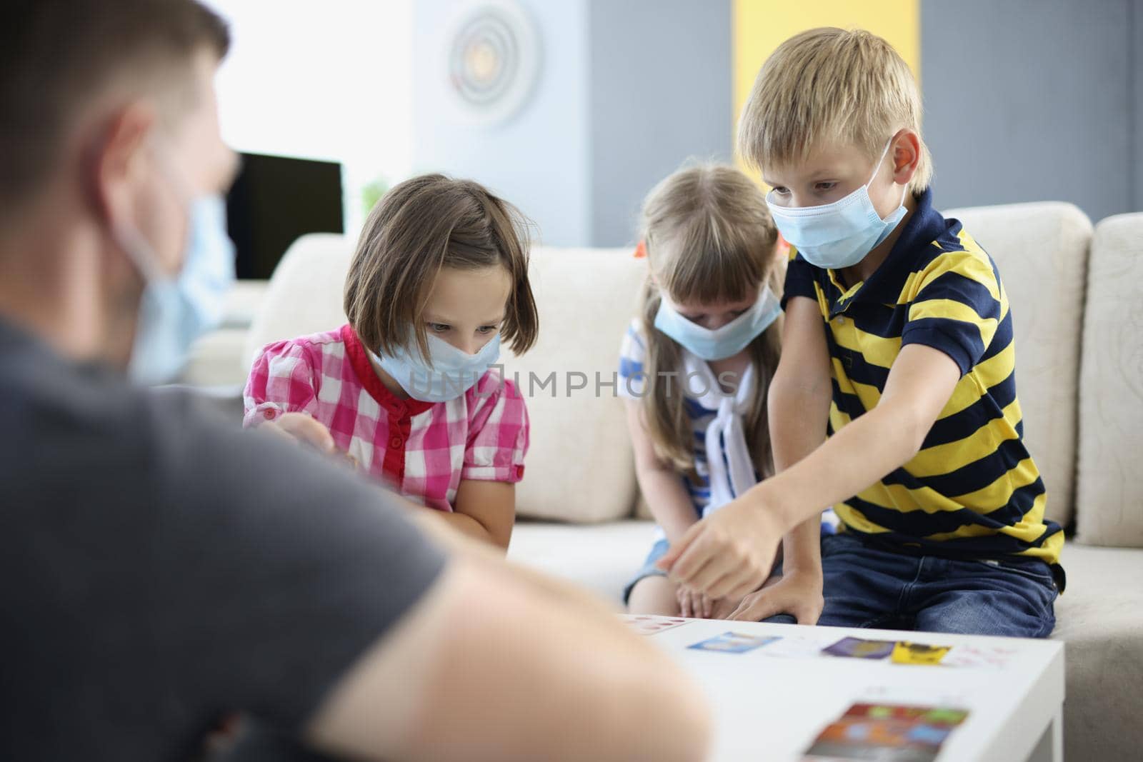 Portrait of children wearing face mask, virus spread in kindergarten, covid spread prevention. Kids playing card game with teacher. Flu, quarantine concept