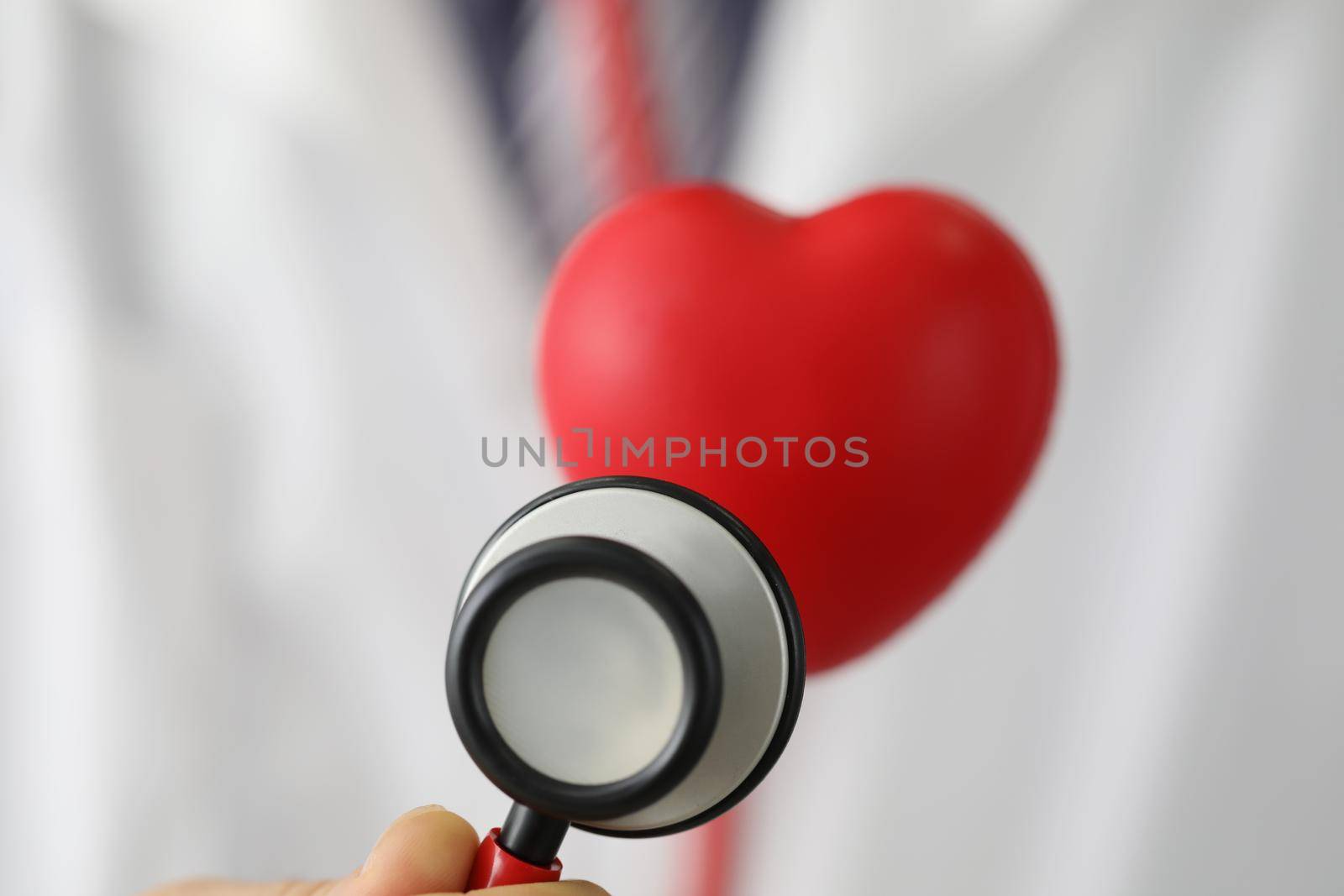 Close-up of medical stethoscope instrument listen to red plastic heart. Save life, full body checkup. Medicine, cardiology, healthcare, analysis concept