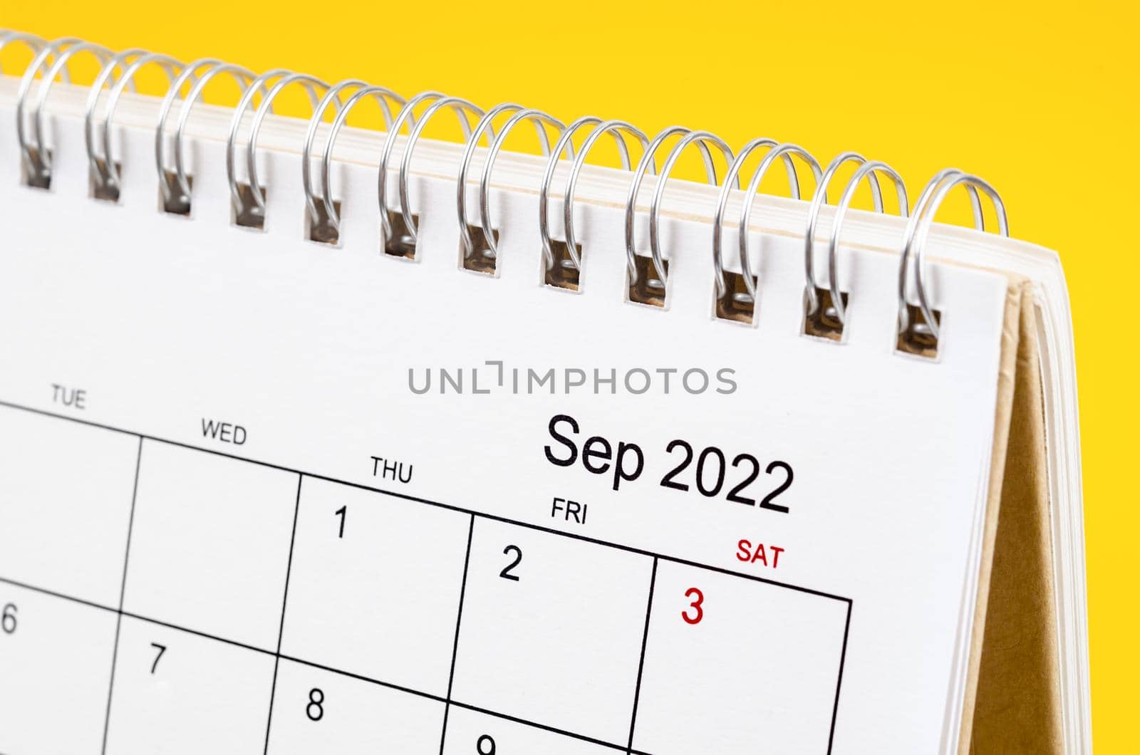 Close-up September 2022 desk calendar on yellow background.