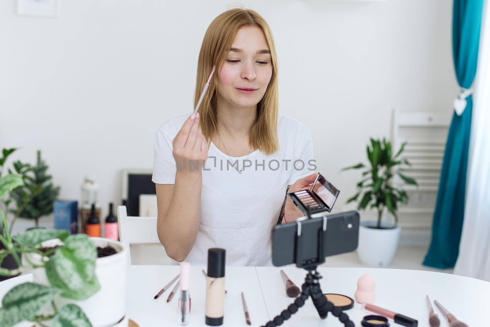 Vlogger testing decorative cosmetic and broadcast live video to social network at home. Blogging, videoblog, makeup concept.