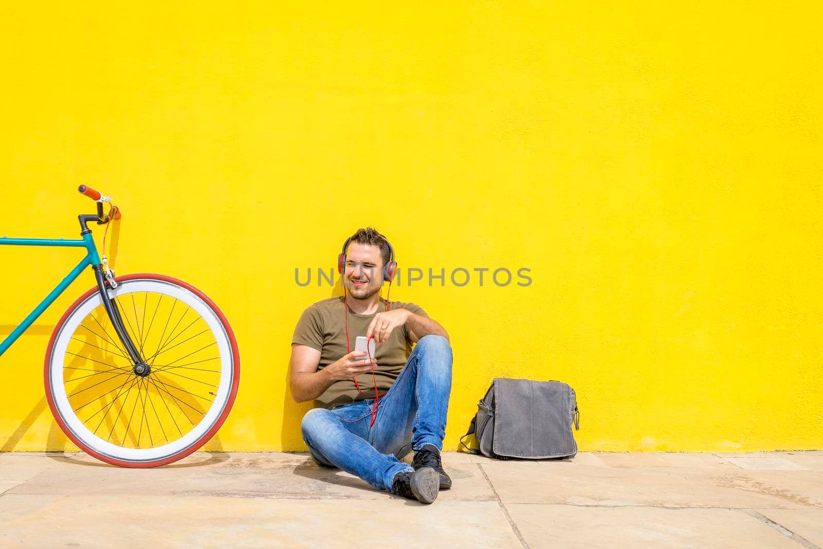 Young male working on laptop sitting on floor. Guy with computer reading news, surfing net or freelancing.