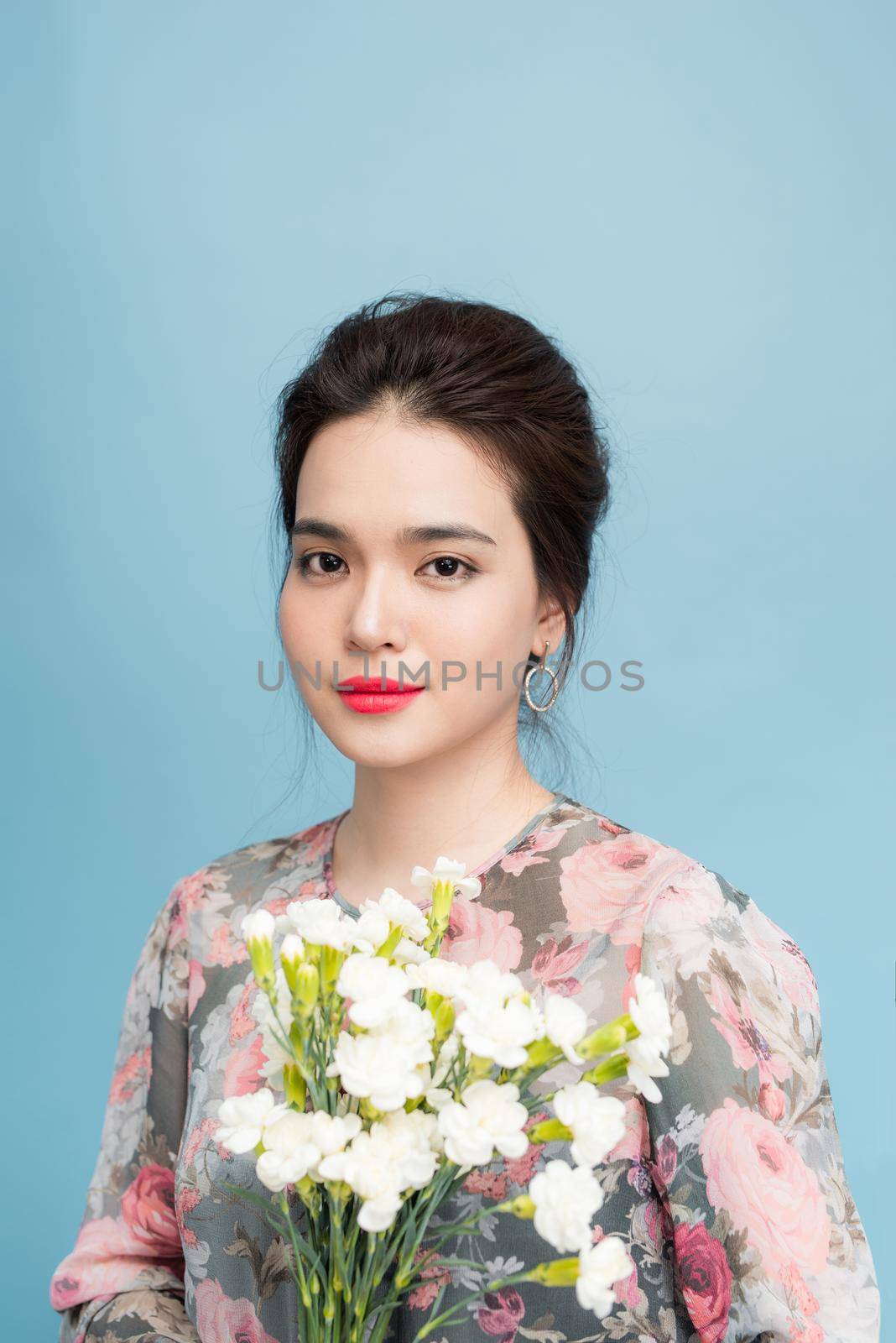 Portrait of tender asia woman with bouquet  on blue background