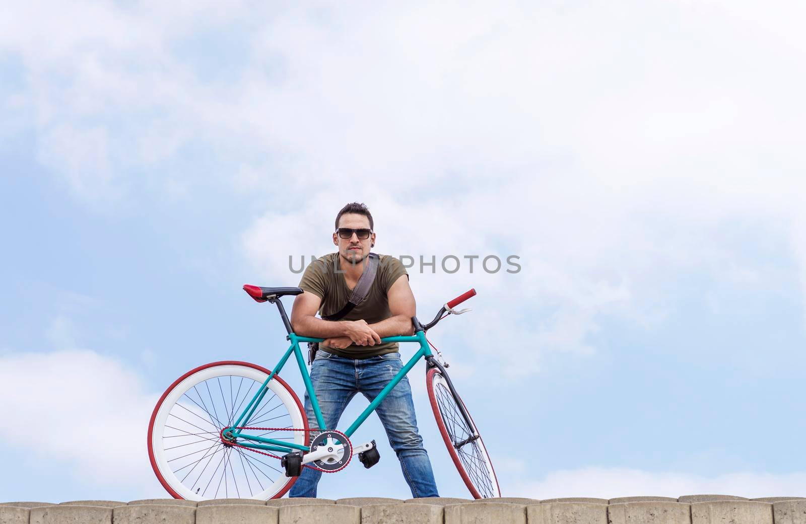young hipster man riding fixed gear bike on city street
