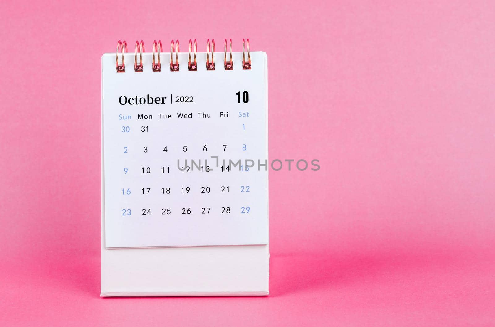 The October 2022 desk calendar on pink background.