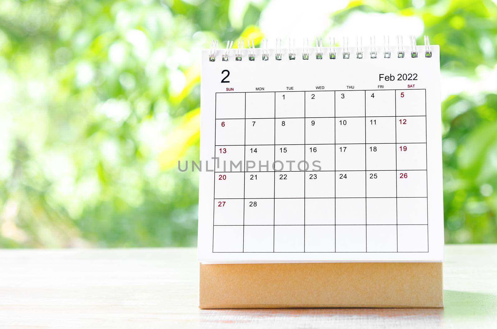 The February 2022 Calendar desk for organizer to plan and reminder on wooden table on nature background.