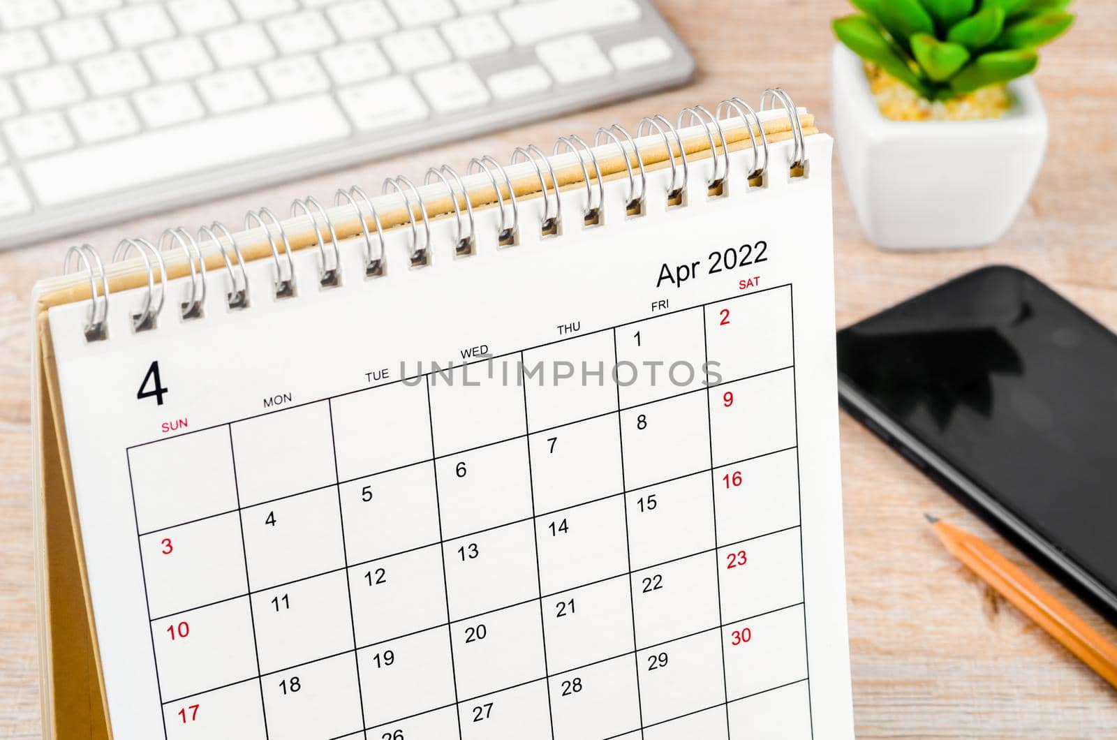 The April 2022 desk calendar on wooden table.