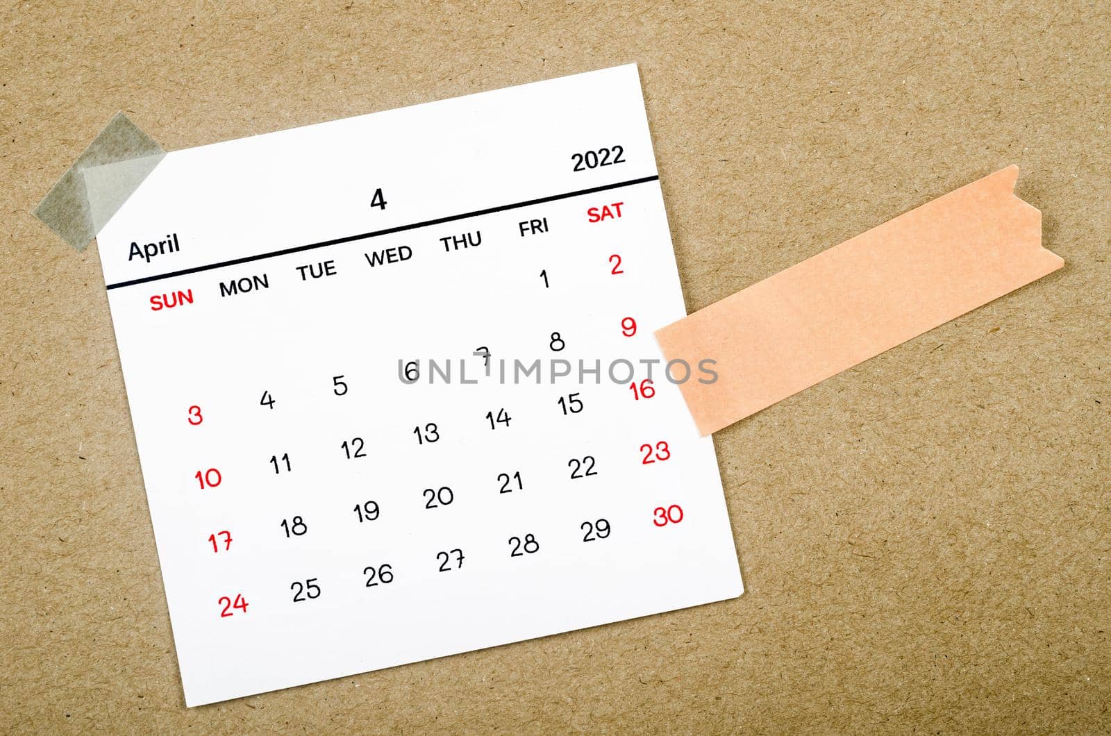 April 2022 calendar with blank adhesive note paper on brown background.