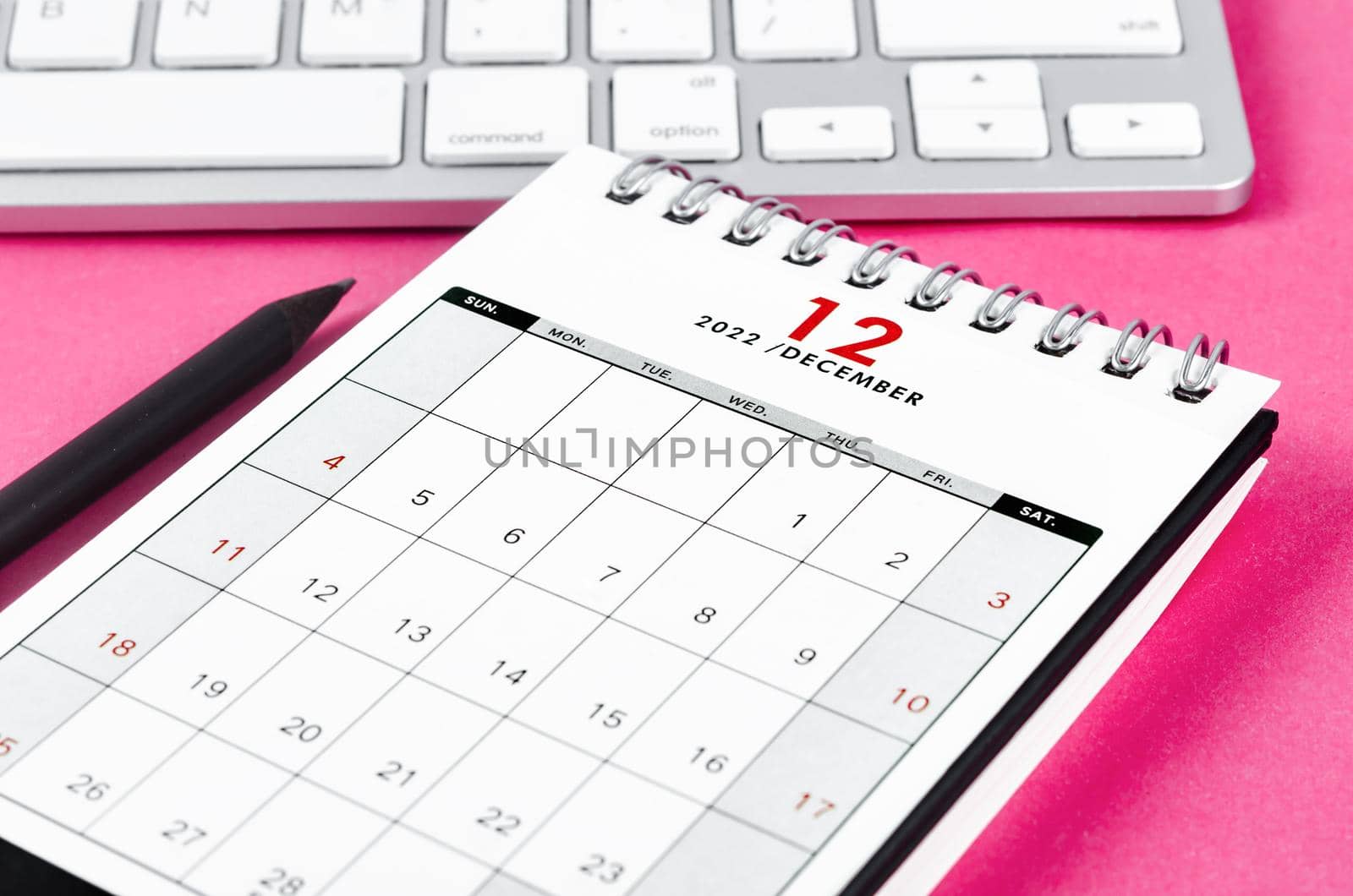 The December 2022 desk calendar with pencil on pink background.