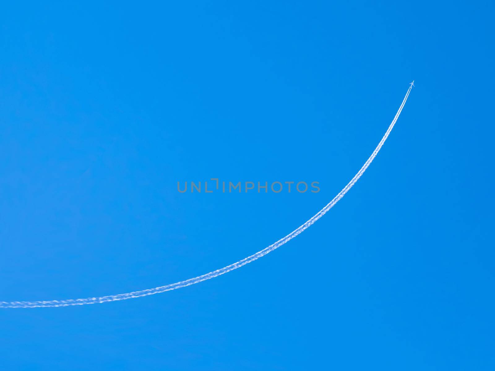 airplane contrail against clear blue sky with copy space