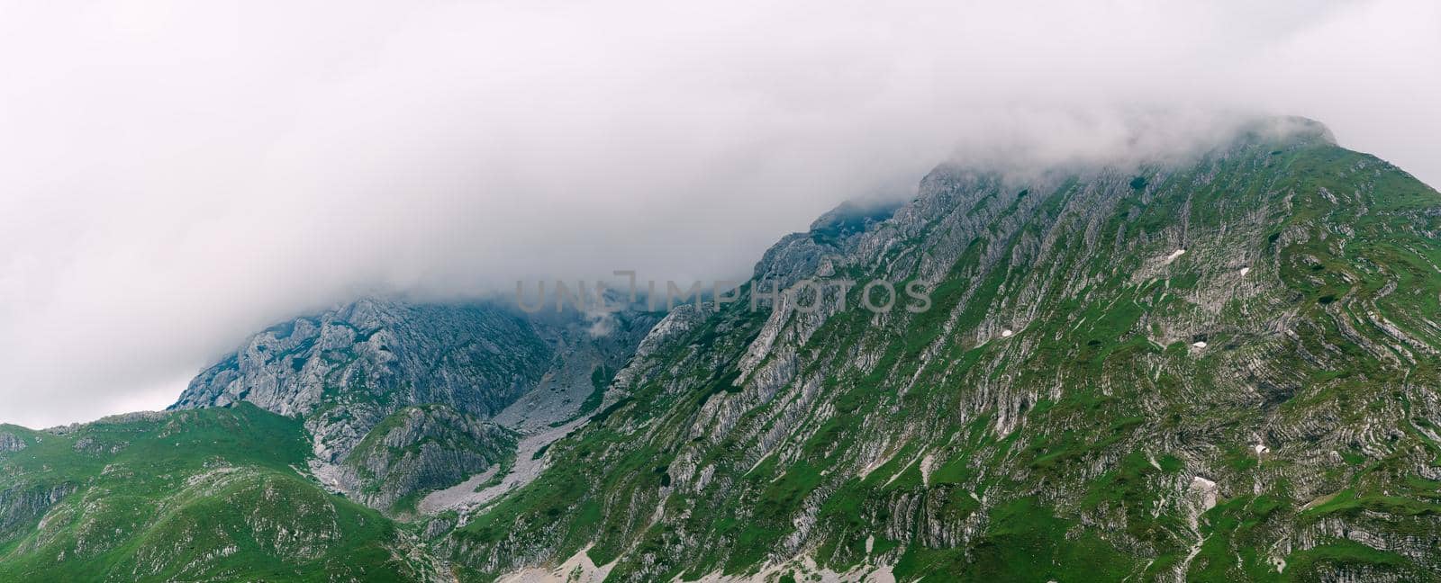 Thick fog envelops the mountain peaks of Durmitor National Park. High quality photo