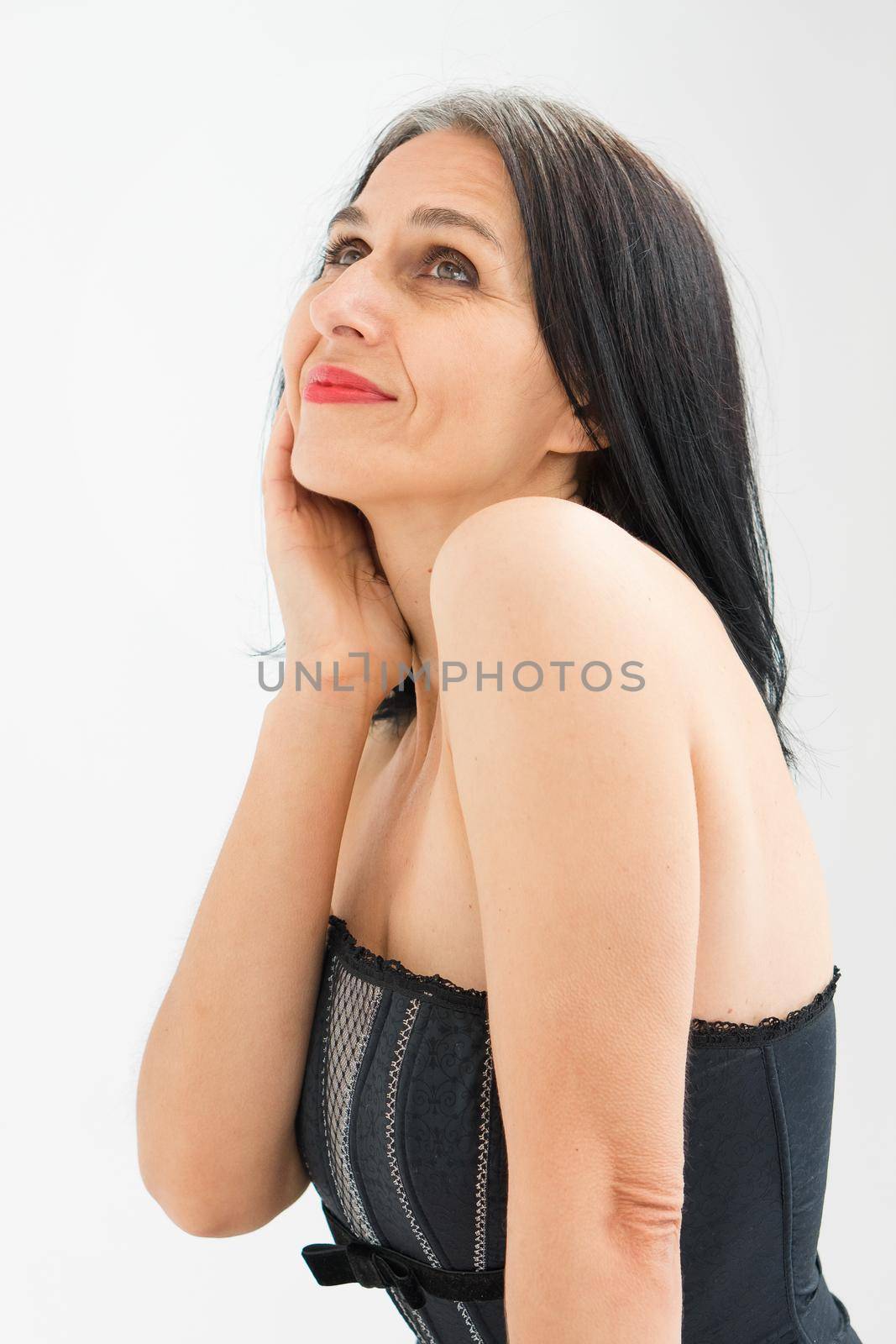 Studio photo of middle aged woman starting getting grey-haired wearing black and white clothes on white background, middle age sexy lady, happy life concept.